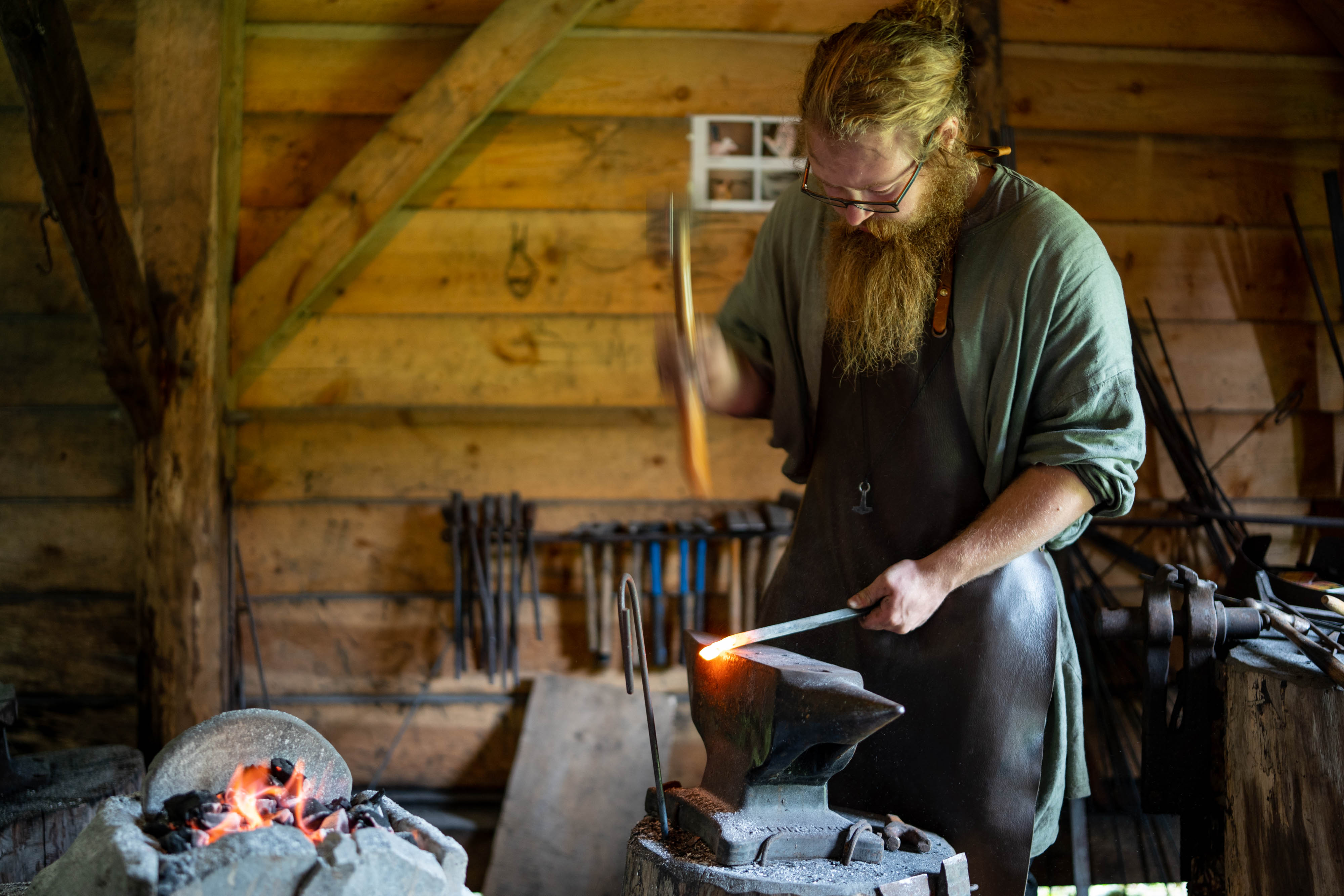 Ein smed hamrar laus på eit stykke glødande metall på ein ambolt i smia.