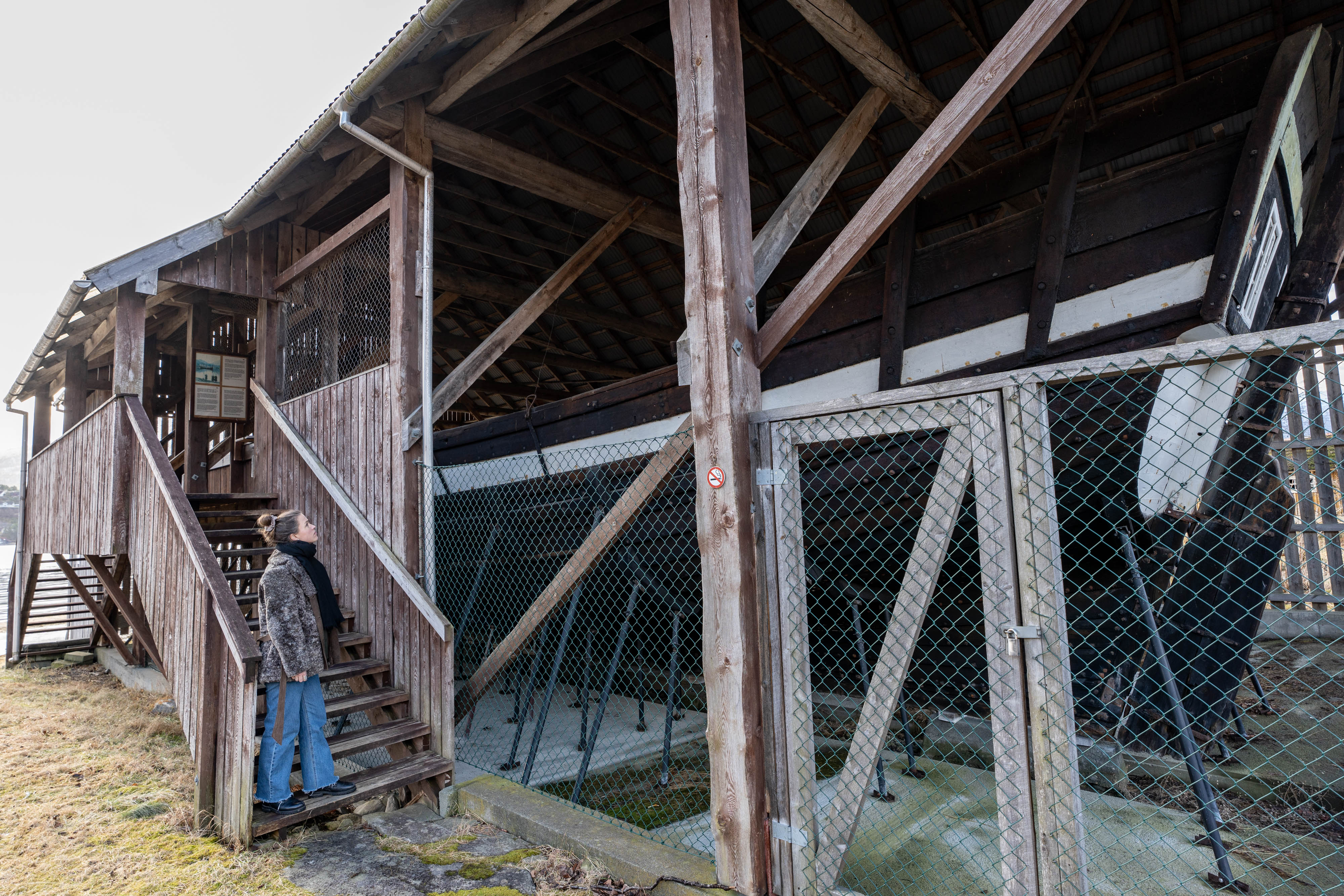 Anne Kristin Moe står i ei gamal tretrapp som del av den opne tre-konstruksjonen som dekker Holvikejekta i dag.