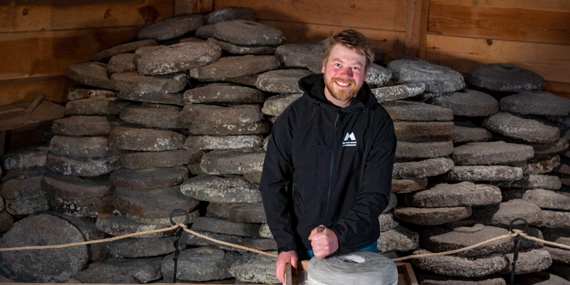 Man in front of pile of millstones.