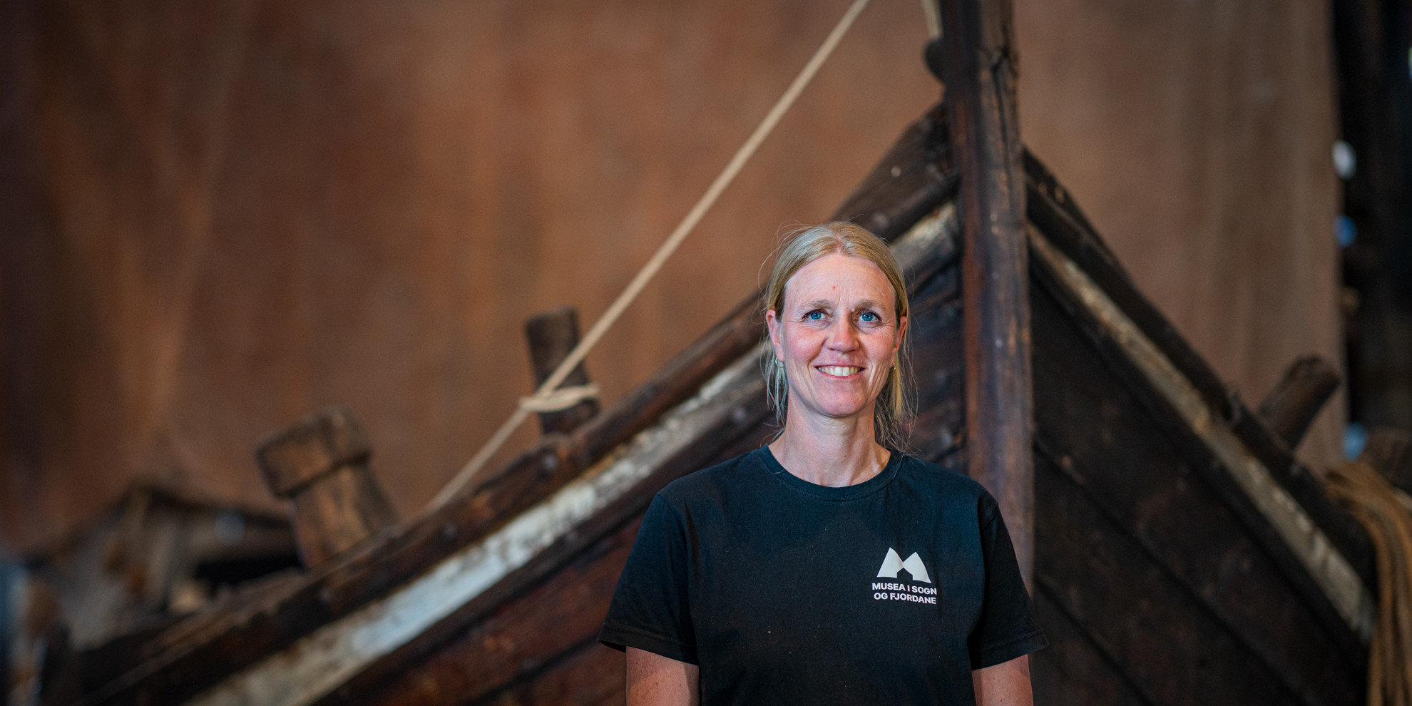 Woman in front og old sail boat with sail.