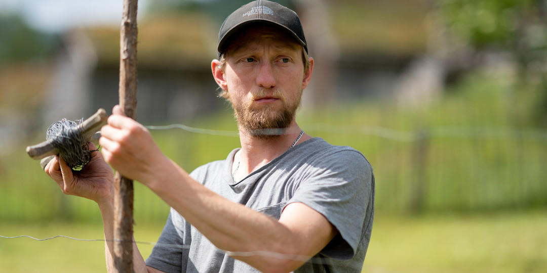 Mann dreg opp hesjestreng og surrar på ein staur