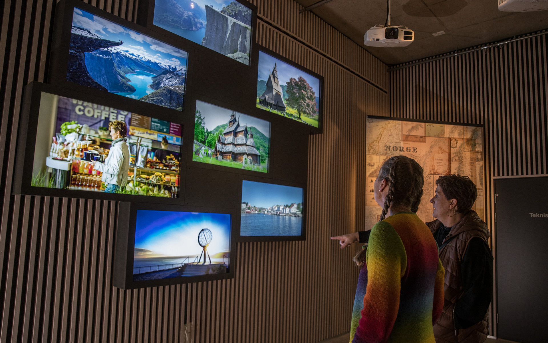 Gjester ser på ei utstilling av bilder av berømte reisemål.
