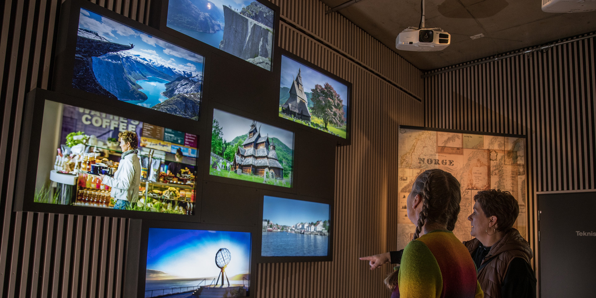 Gjester ser på ei utstilling av bilder av berømte reisemål.