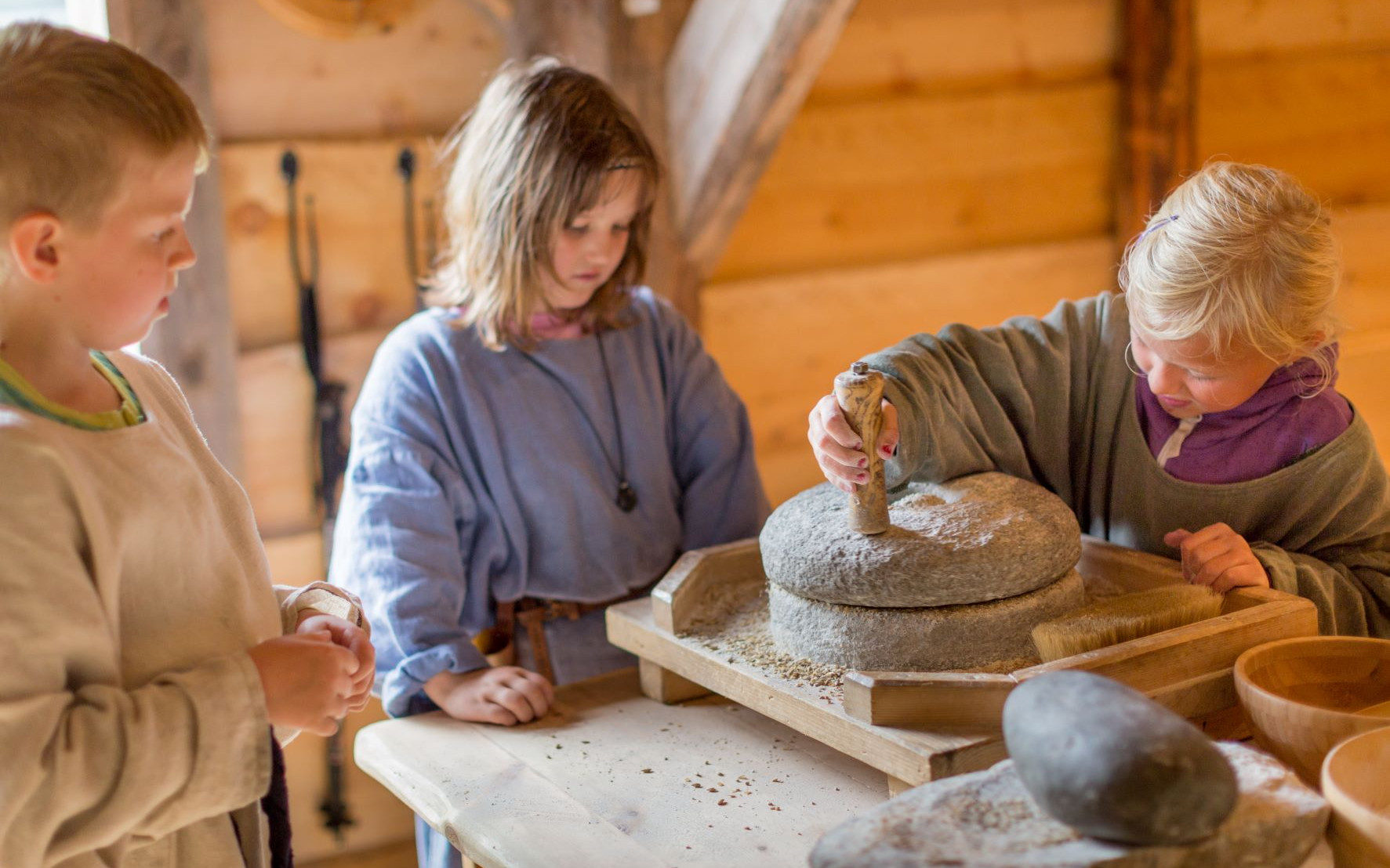 Born i vikingkle male korn om til mel med ei gammaldags handkvern.