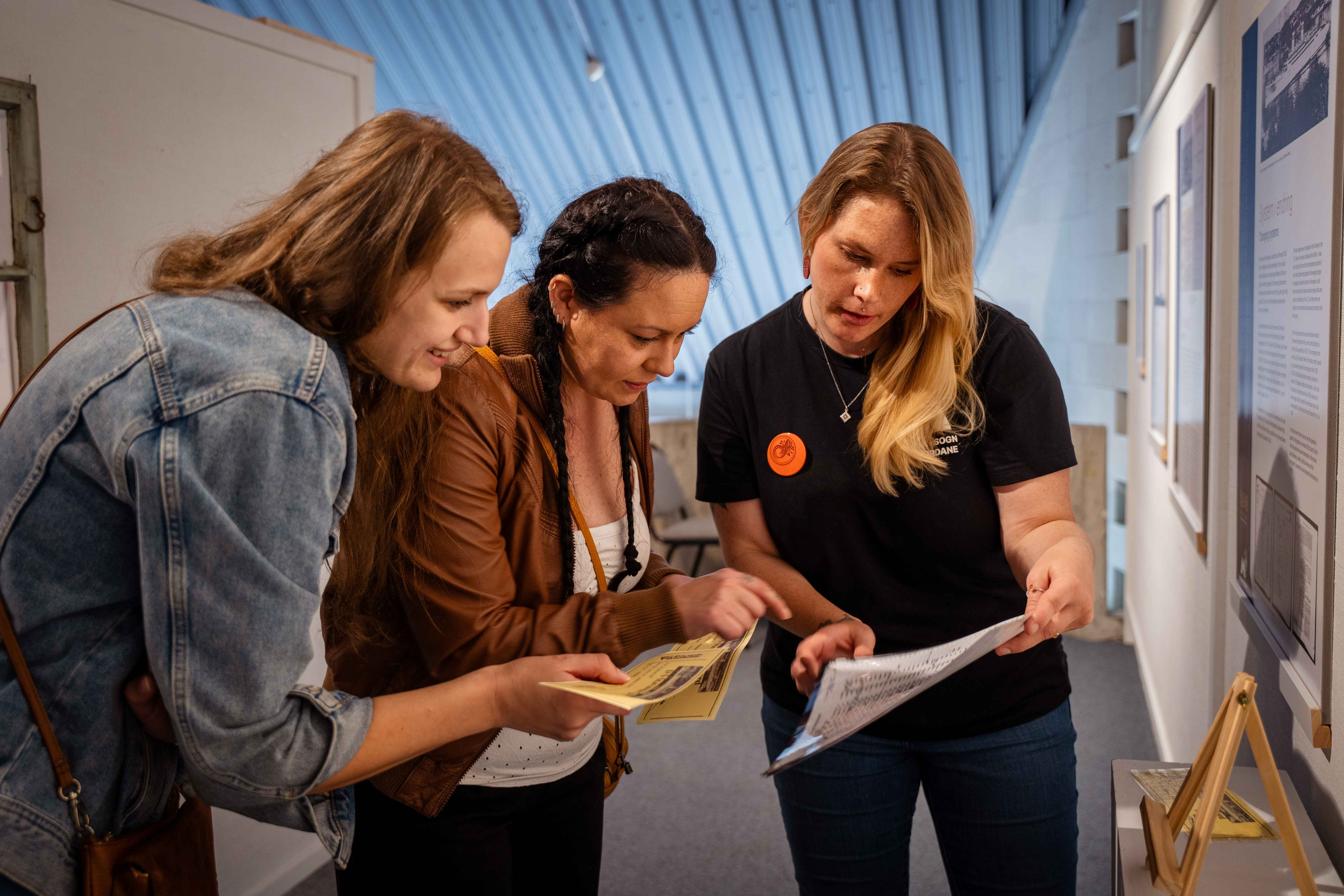 Women examine text materials in an exhibit.
