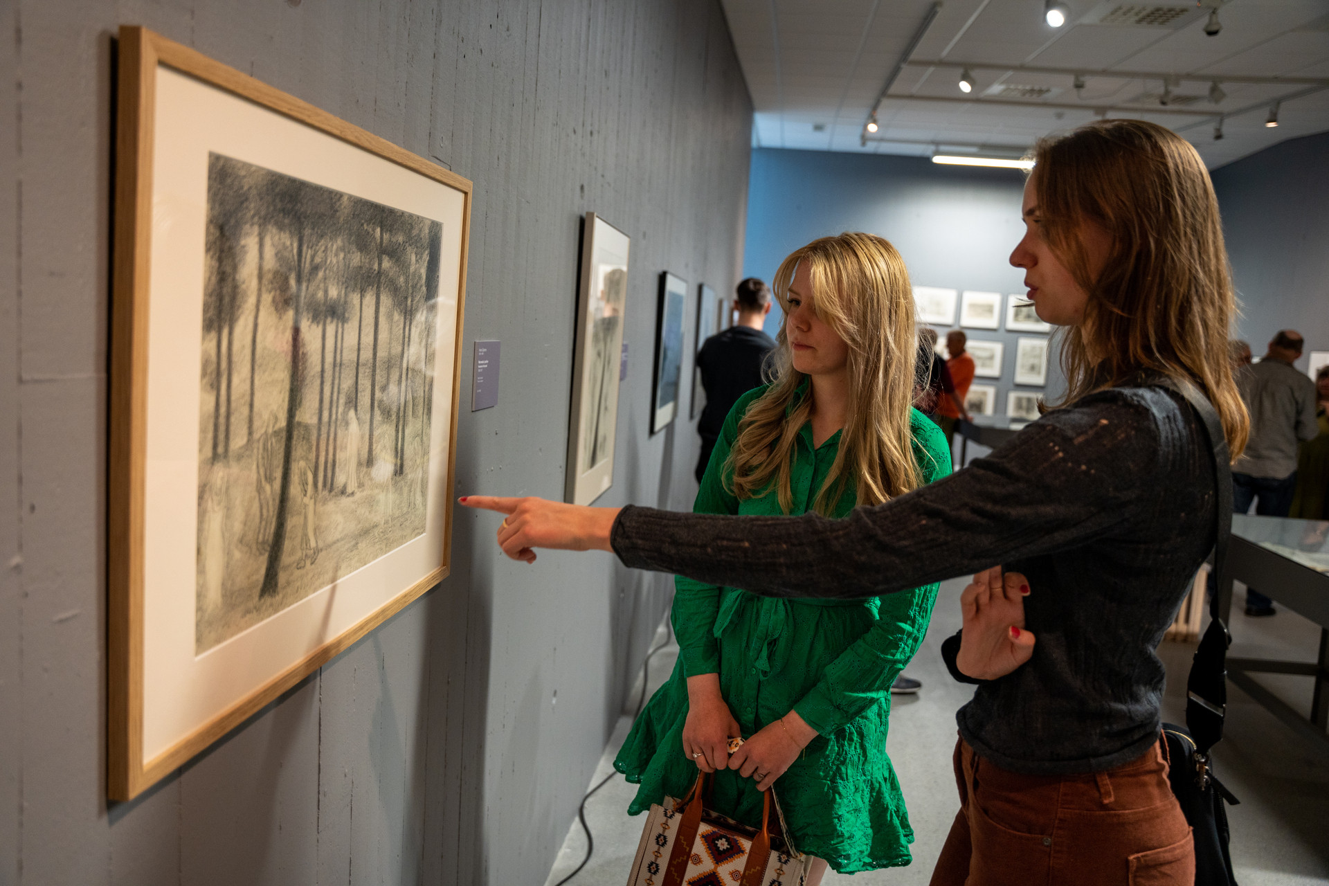 Two women looks at art.