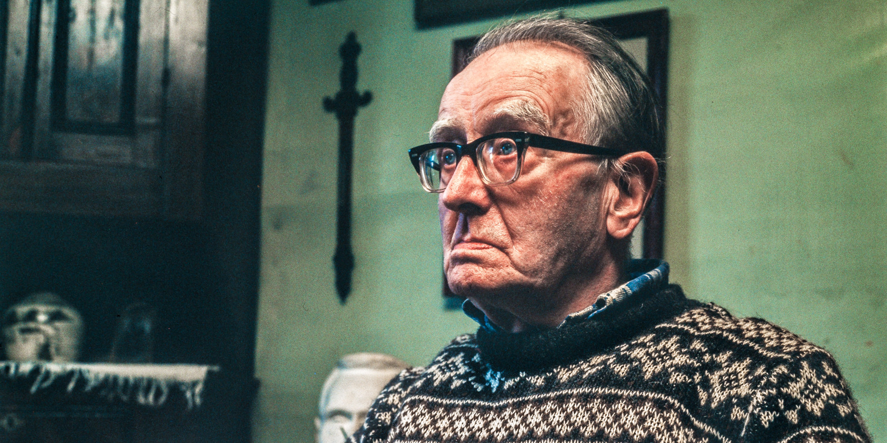 Portrett av Hans Gjesme, gamal mann med strikkegensar og tjukke briller.