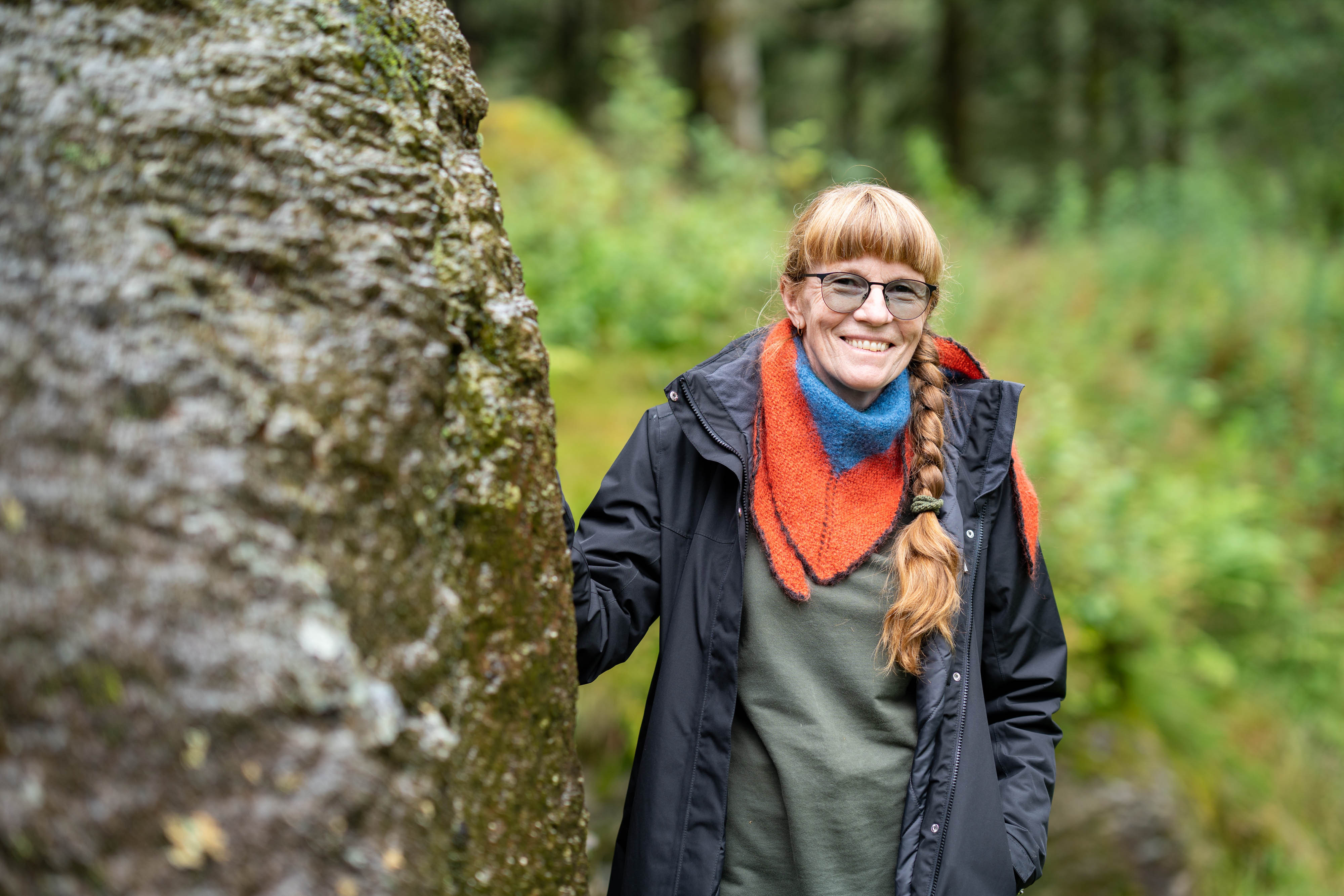 Torunn støttar seg til ein loddrett bergvegg, som syner spor etter uttak av kvernstein.