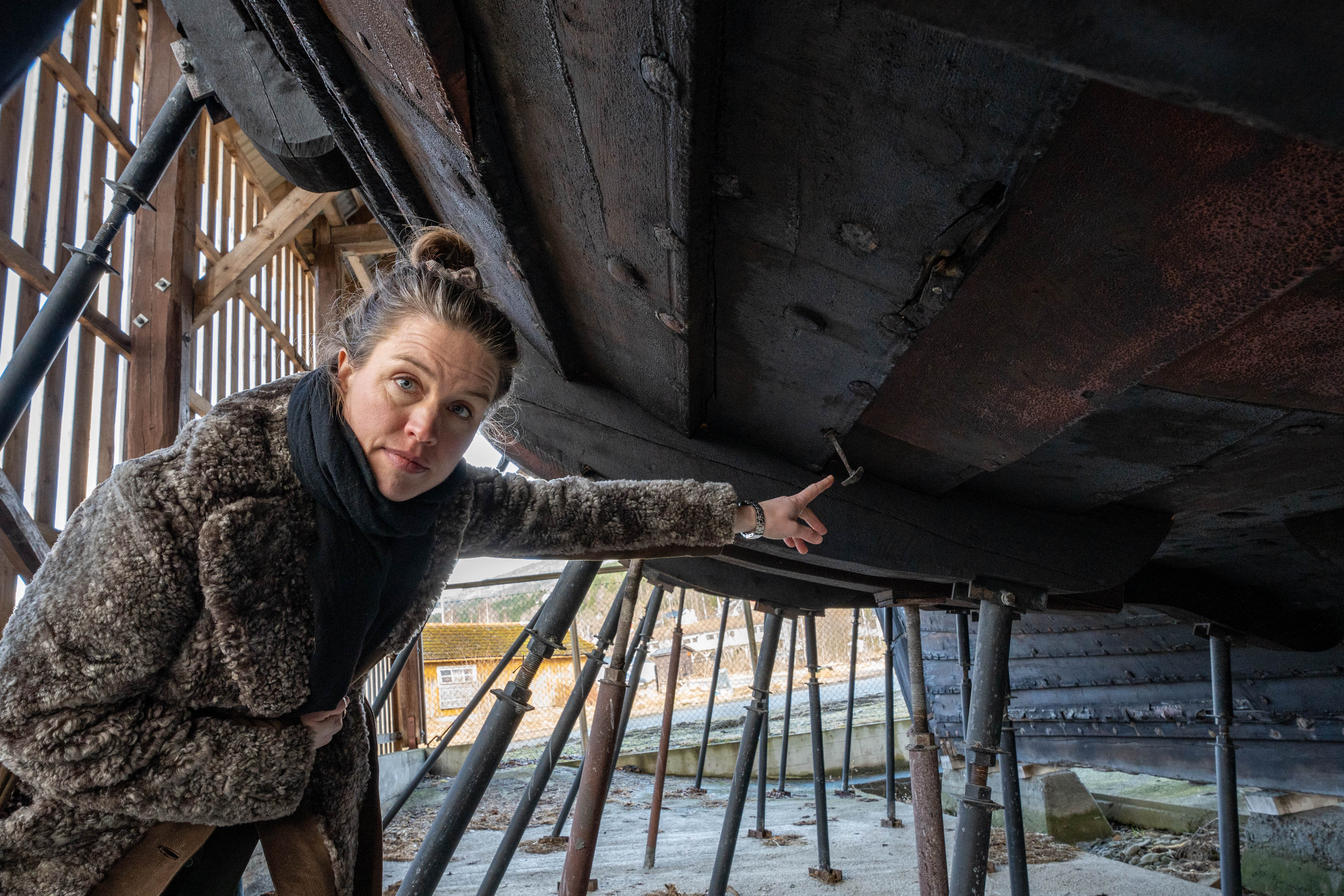 Anne Kristin Moe peikar på ein rusten nagle på veg ut av skutesida.