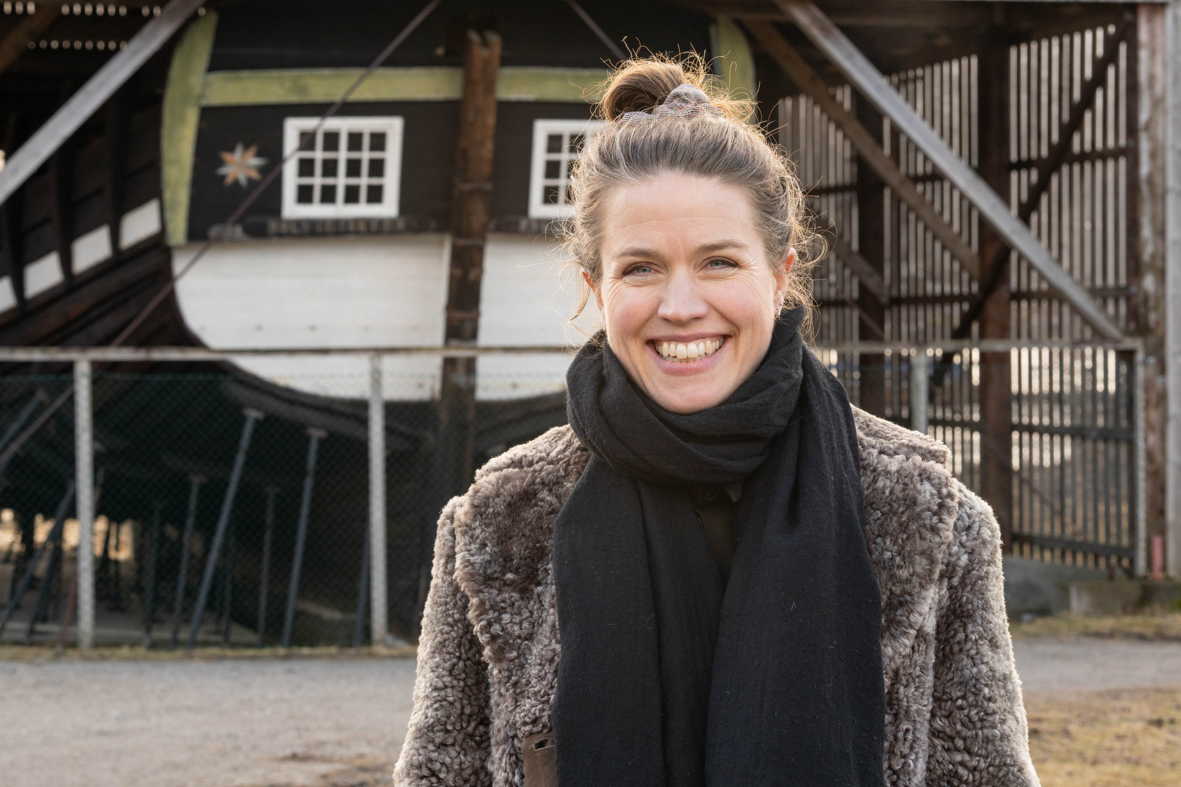 Museumsleiar Anne Kristine Moe smiler med Holvikejekta i bakgrunnen