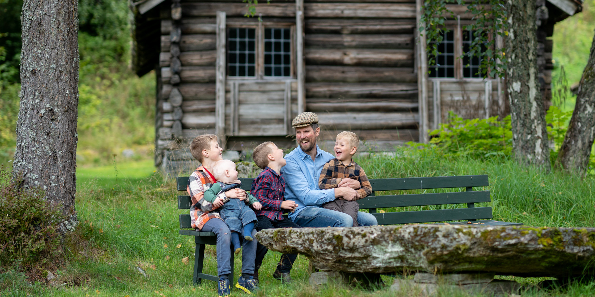 Ein far med fire barn kosar seg på ein benk i friluftsmuseet.
