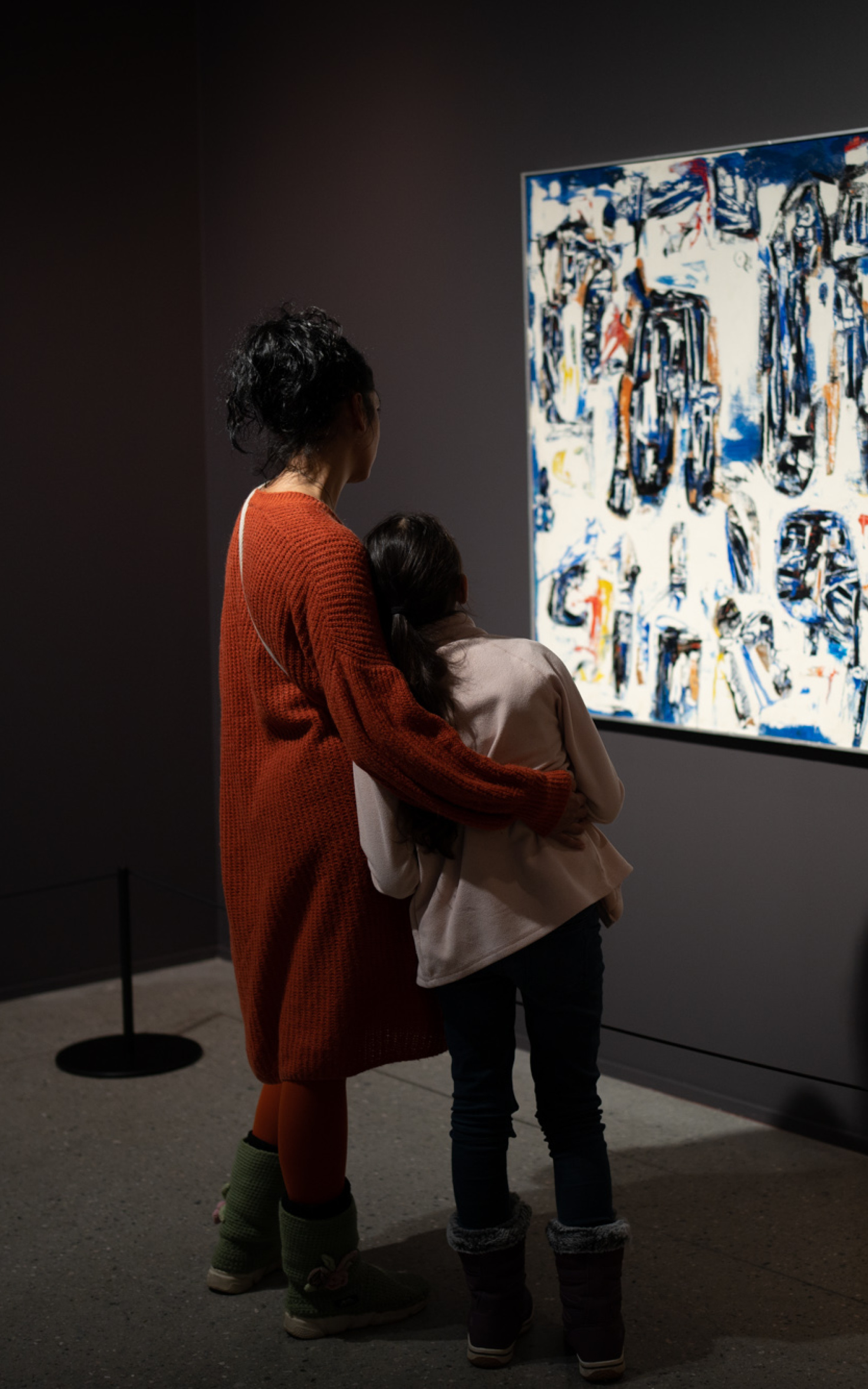 Kvinne og barn ser på eit fargerikt måleri.