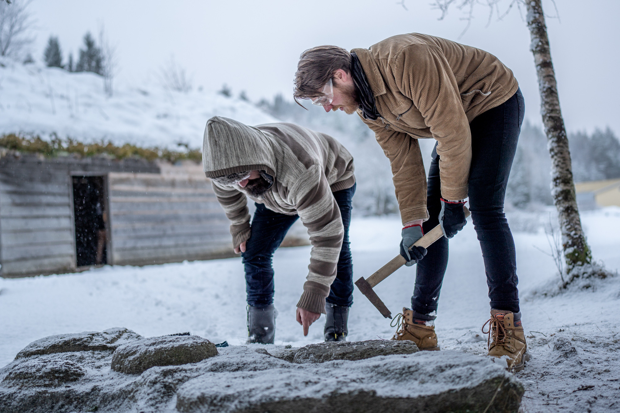 Alexander står med ei steinhakke og Filippo peikar på kva steinen.