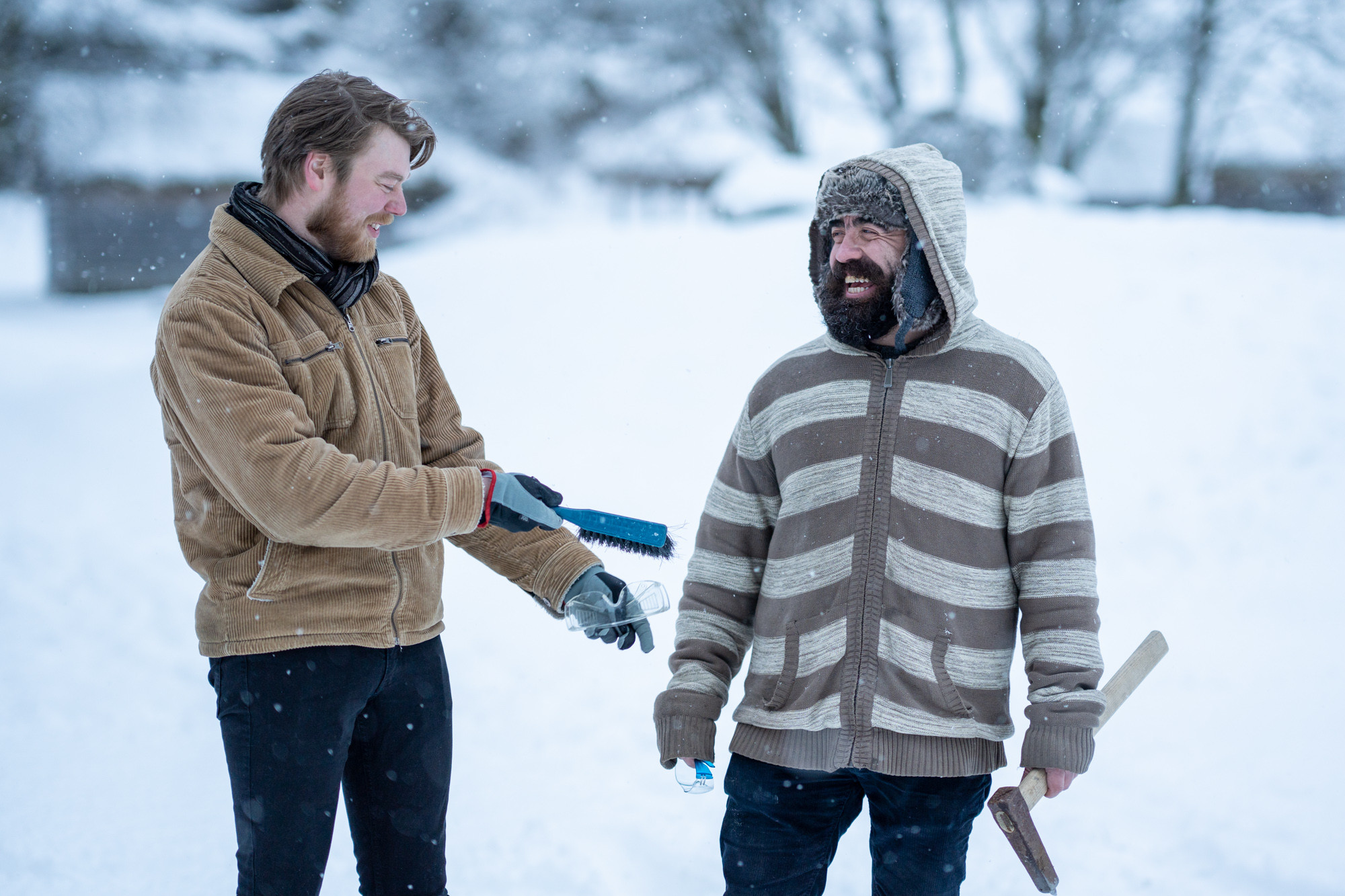 To menn som smiler, ein med kost, ein med steinhakke.