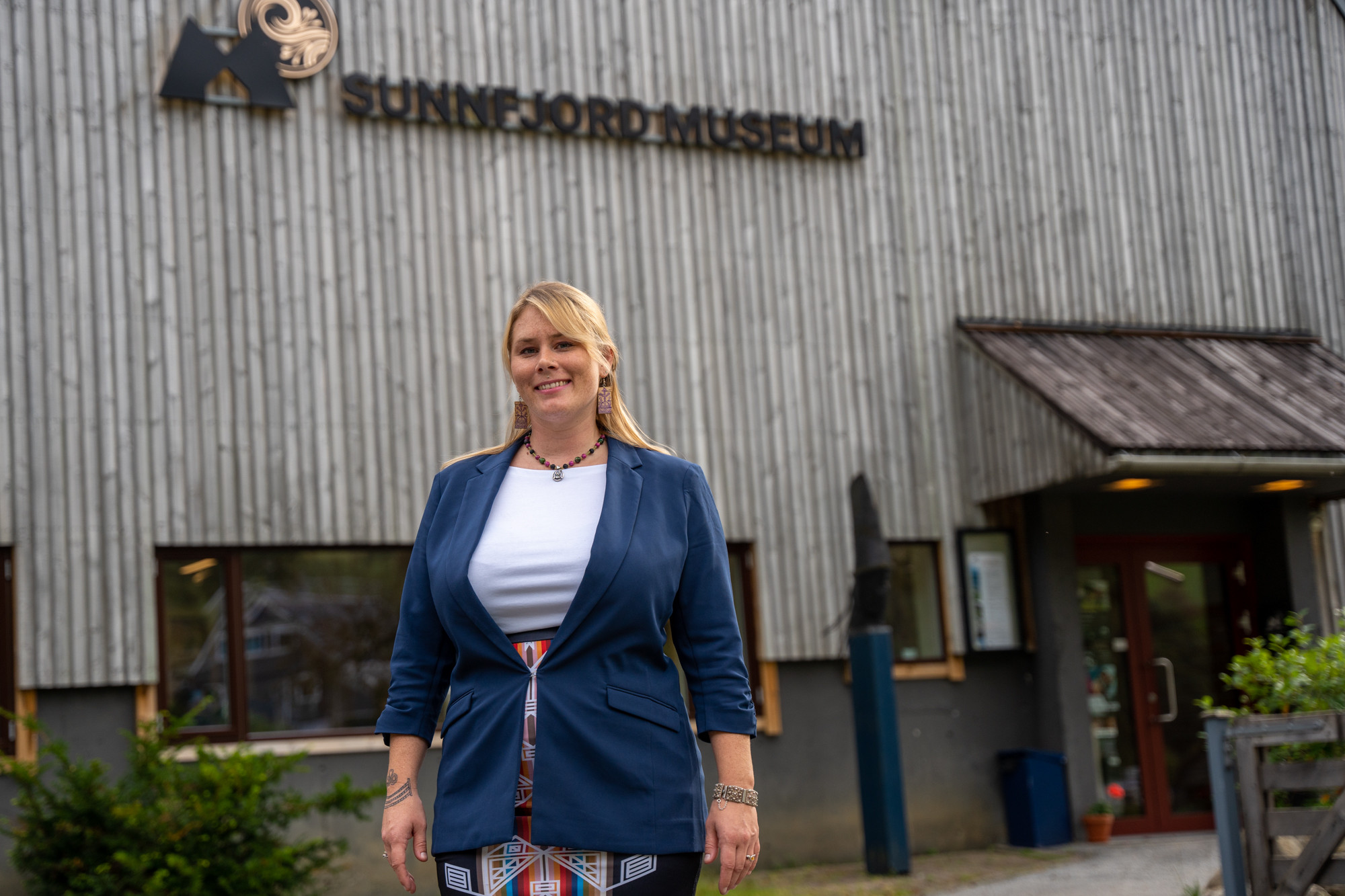 Smilande kvinne med blondt hår framfor Sunnfjord Museum.