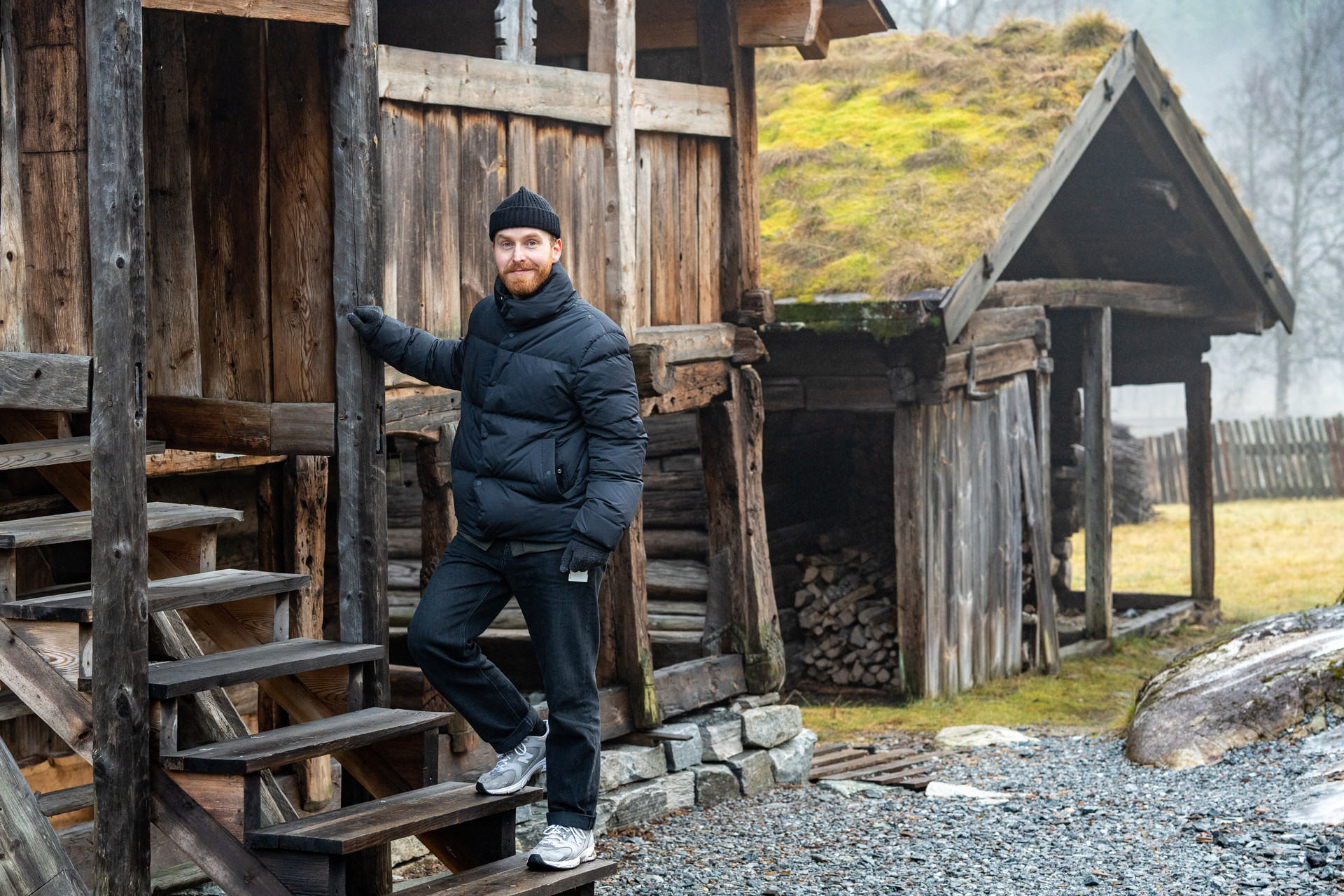 Mann står i trapp på gamalt trehus.