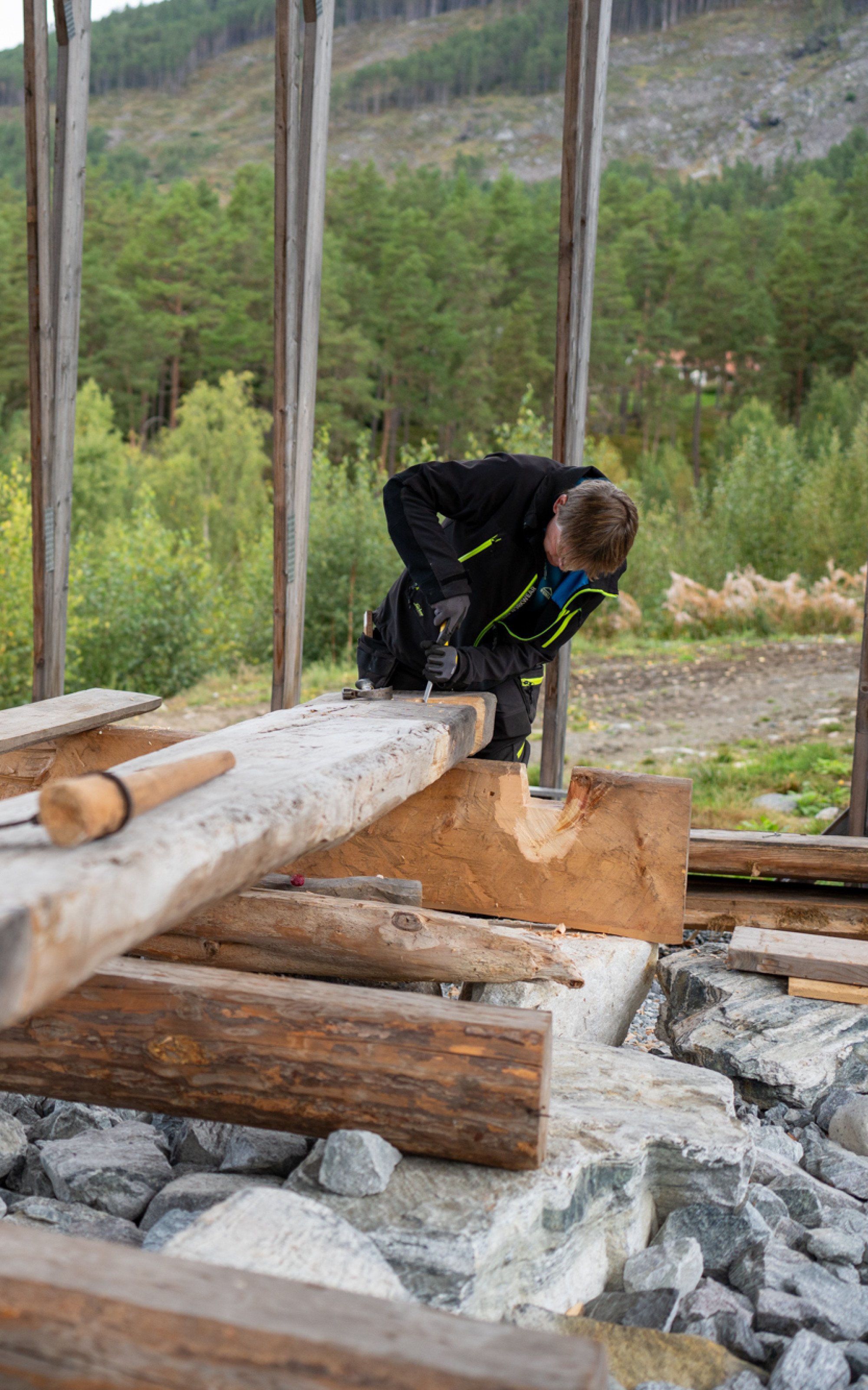 Mann jobbar med hoggjarn på stor stokk.