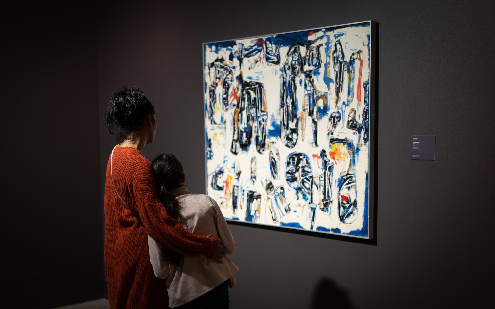 Ei vaksen kvinne og ei jente studerer eit abstrakt måleri i kvitt, blått og svart.