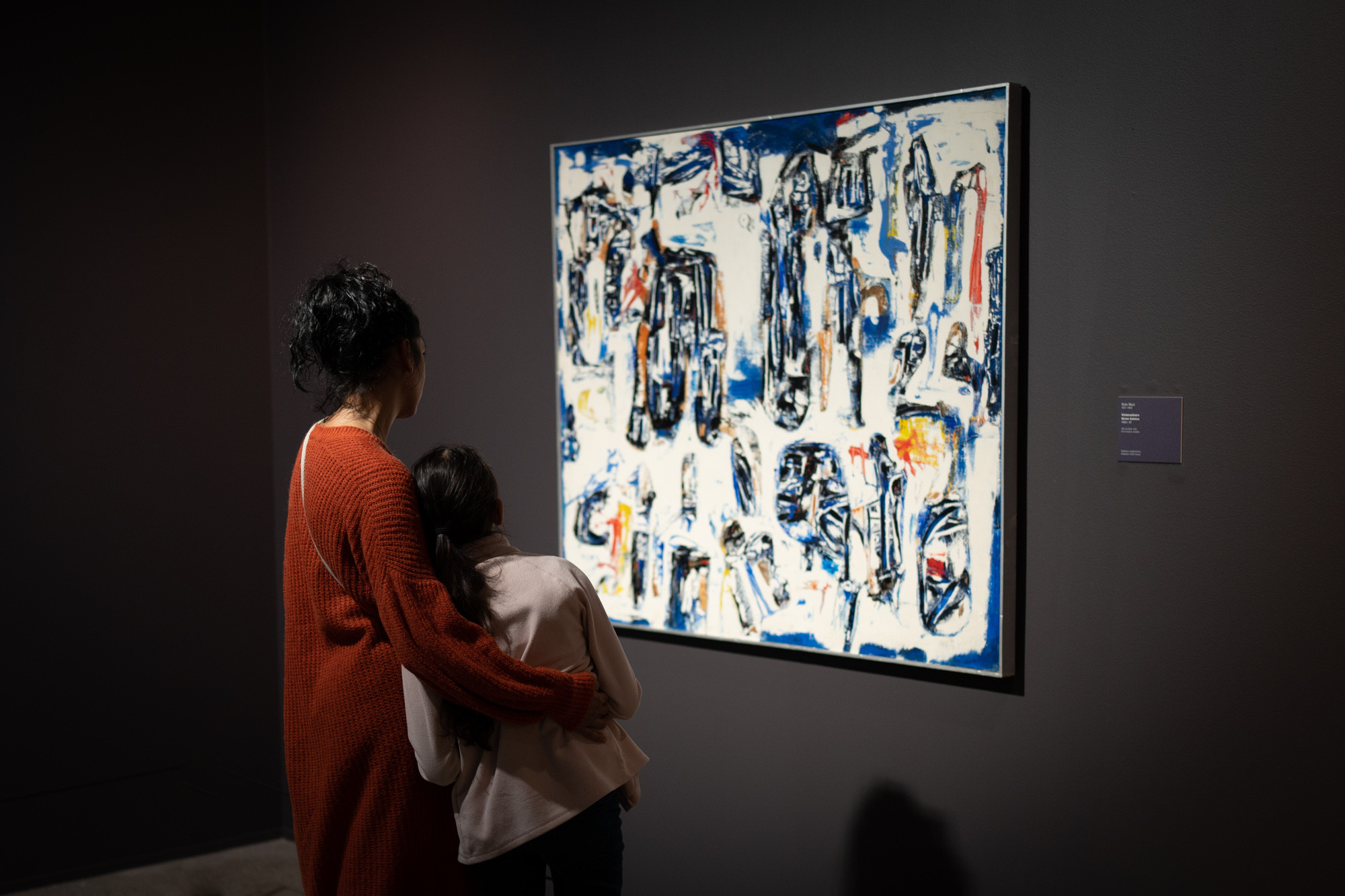 Ei vaksen kvinne og ei jente studerer eit abstrakt måleri i kvitt, blått og svart.