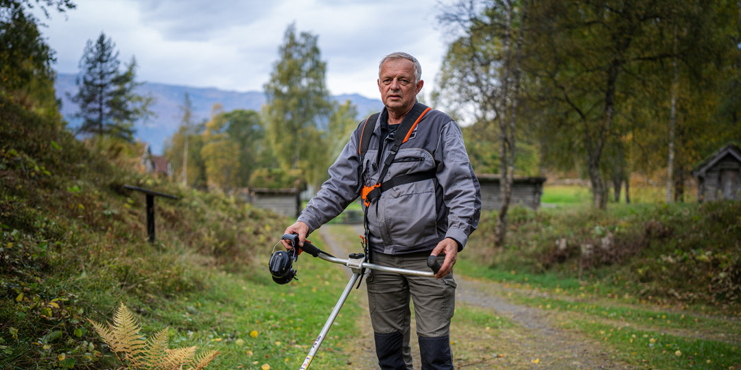 MAnn med arbeidstøy og ryddesag hengande frå sele