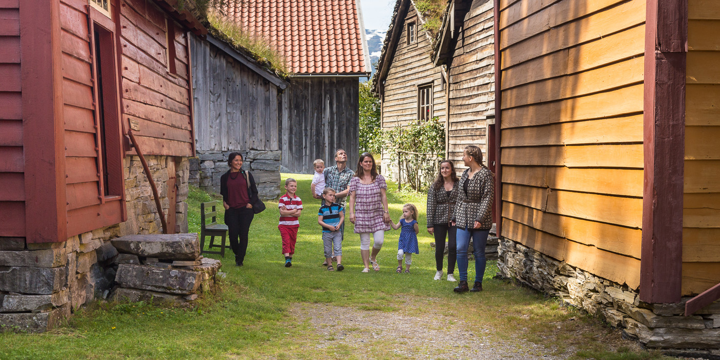 Vaksne og born på omvising i friluftsmuseet på Nordfjord Folkemuseum.