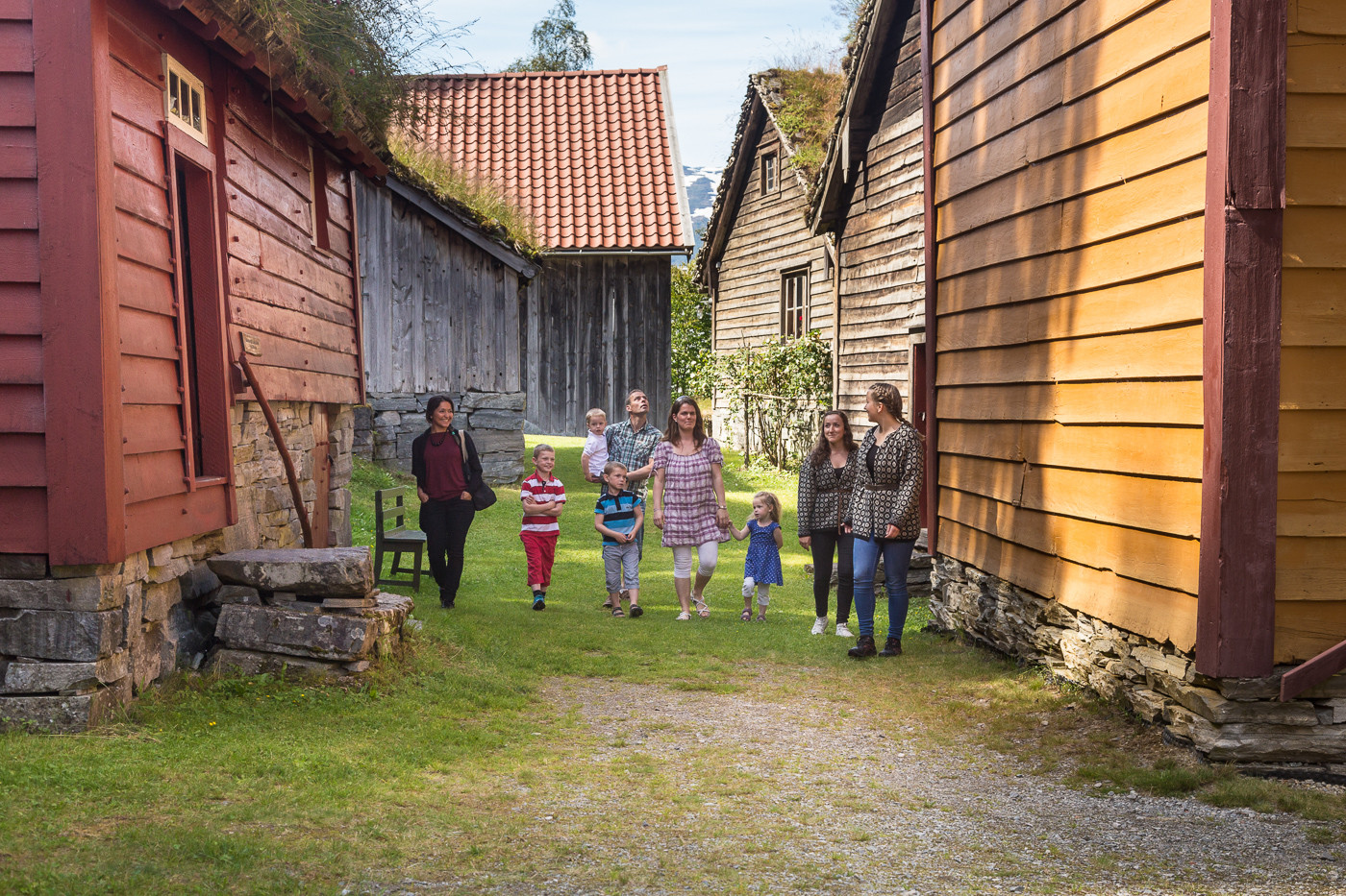 Vaksne og born på omvising i friluftsmuseet på Nordfjord Folkemuseum.