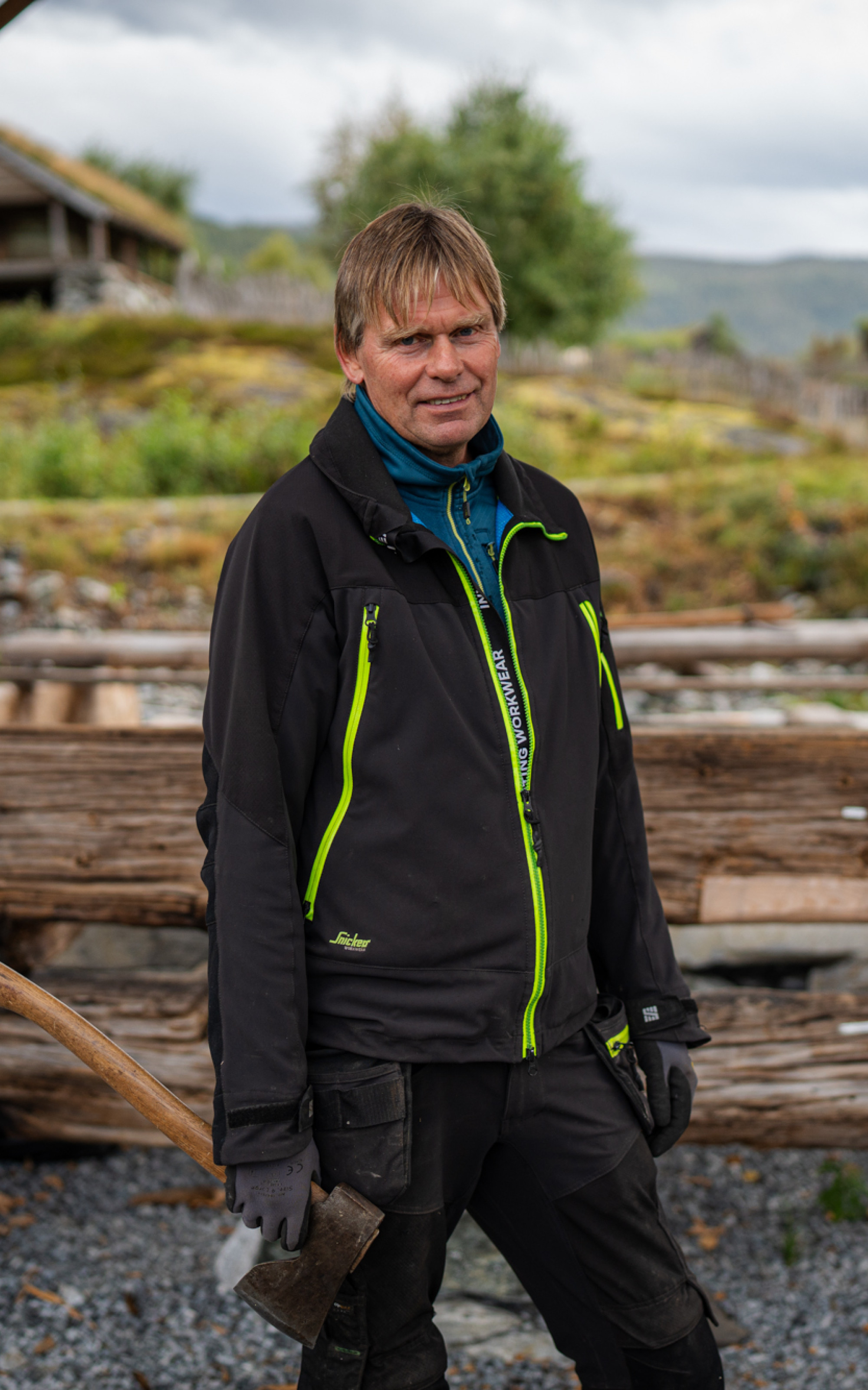 Smilande mann med øks framfor byggetomta.