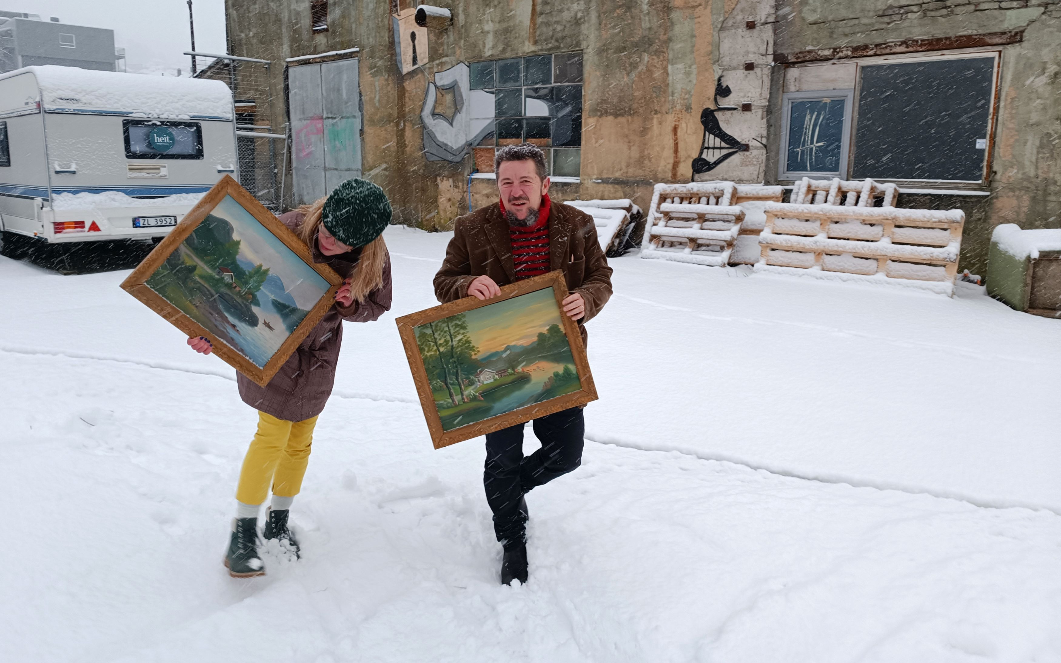 Kunstnarduoen Alt Går Bra går ute i snøvær medan dei ber på to Strandamåleri