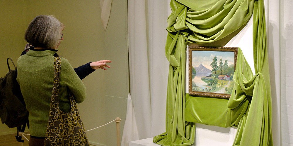 To publikumarar ser på eit måleri i utstillinga Kunst i dei tusen heimar.