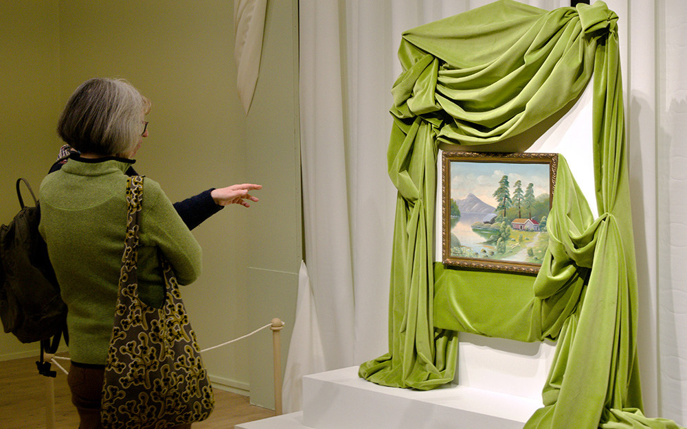 To publikumarar ser på eit måleri i utstillinga Kunst i dei tusen heimar