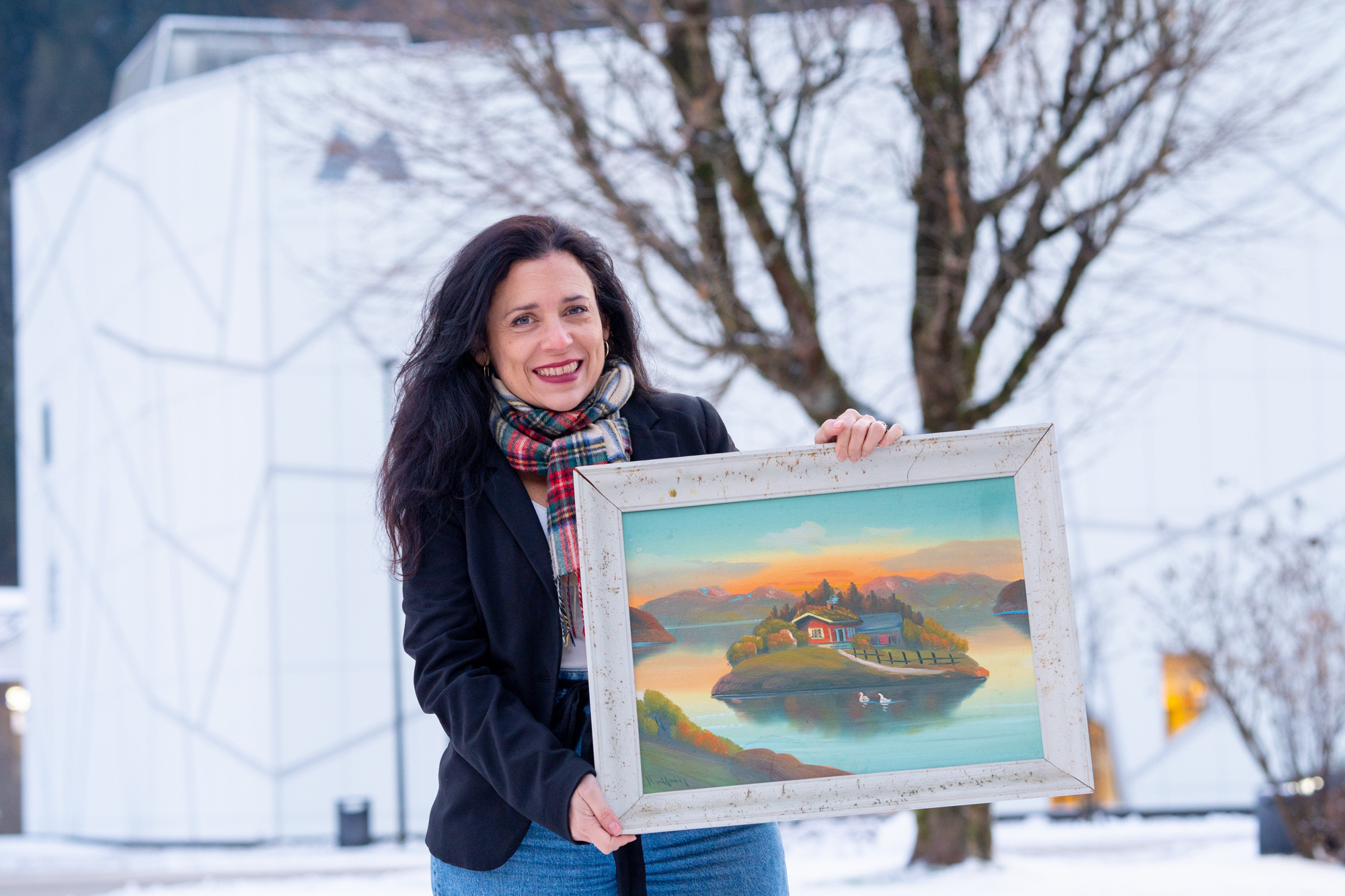 Museumsleiar Mayra Henriquez står framfor Kunstmuseet i Sogn og Fjordane og held opp eit strandamåleri.