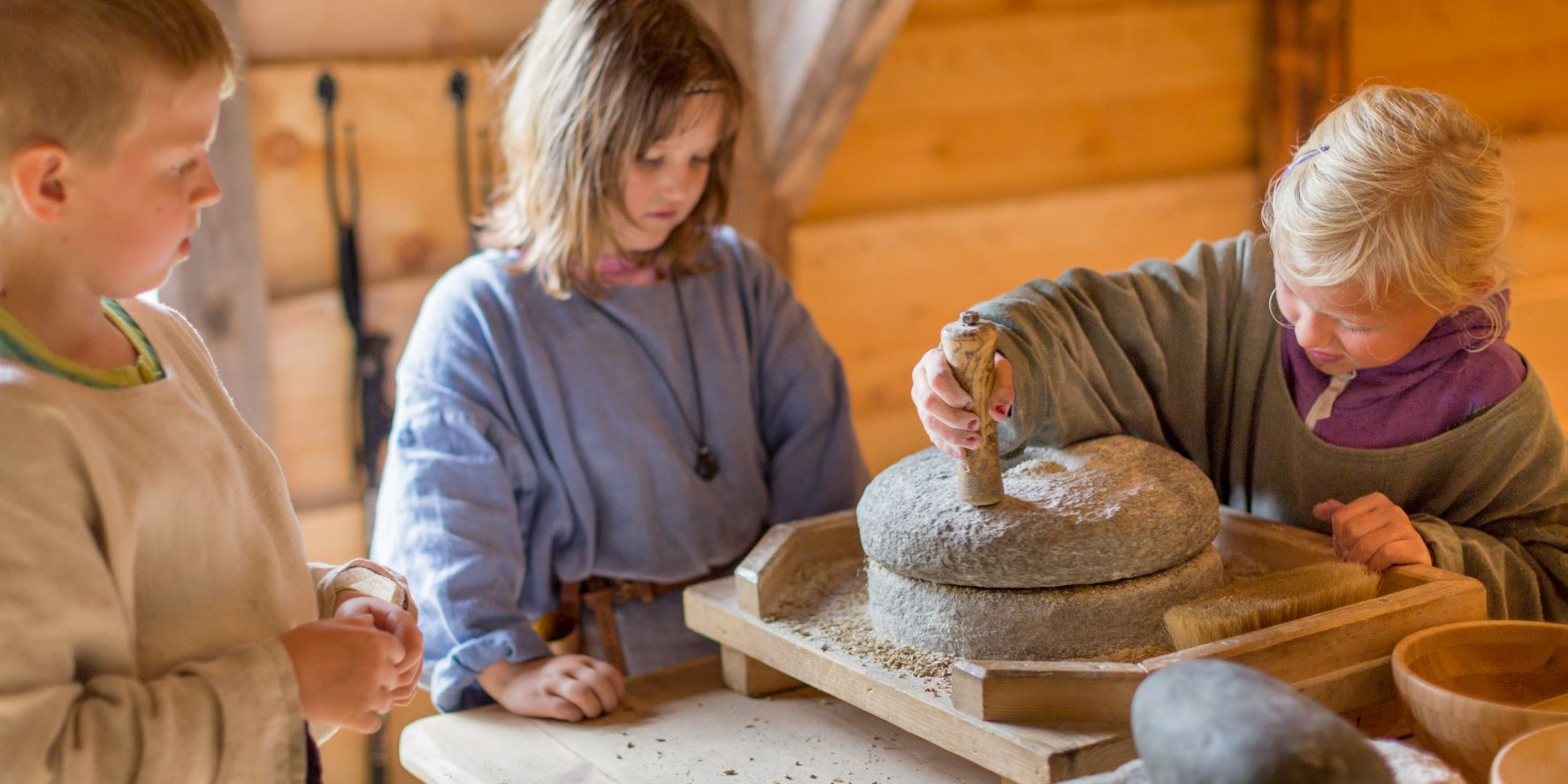 Born i vikingkle male korn om til mel med ei gammaldags handkvern.