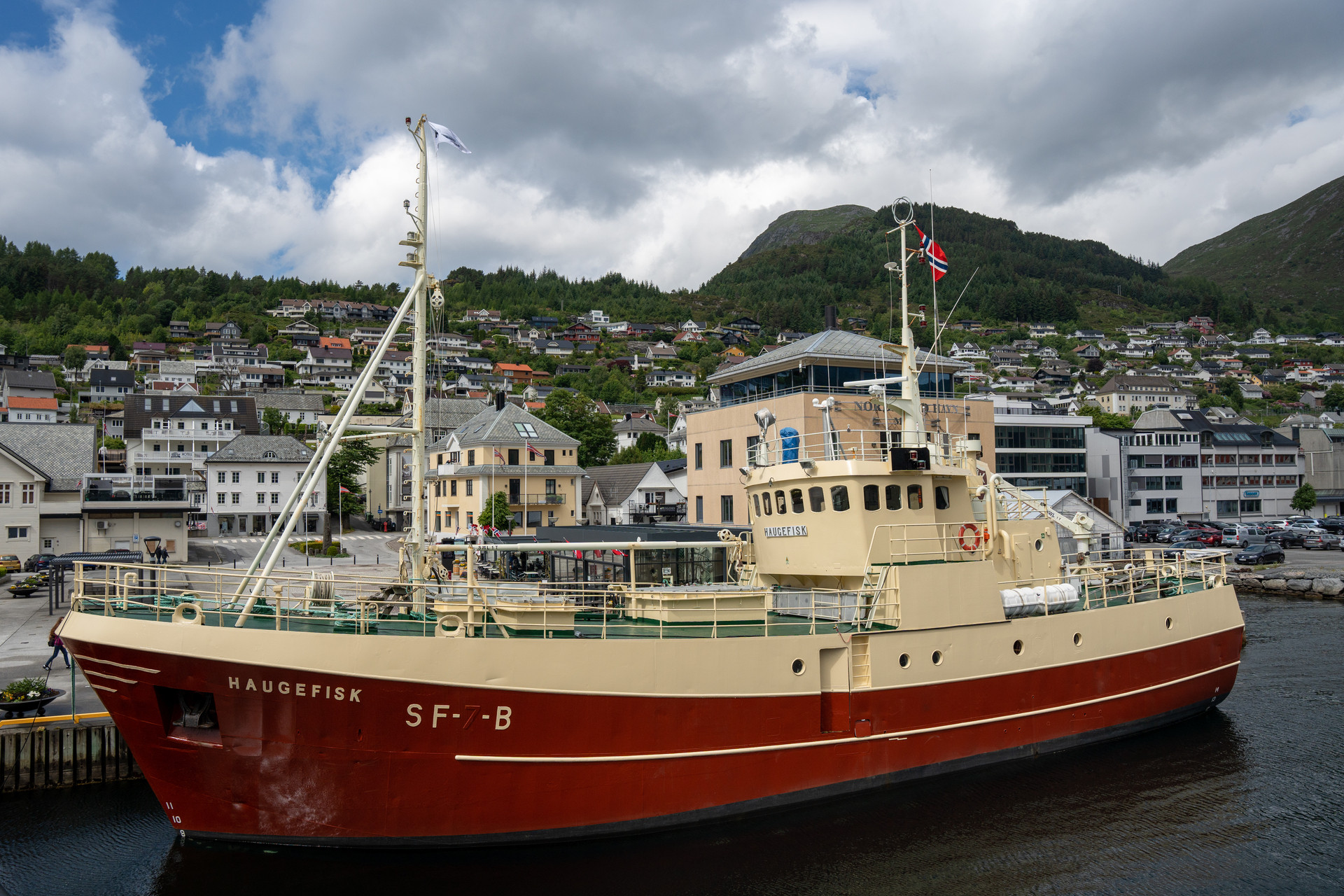 Fiskebåt ligg til kai framfor begyggelse.