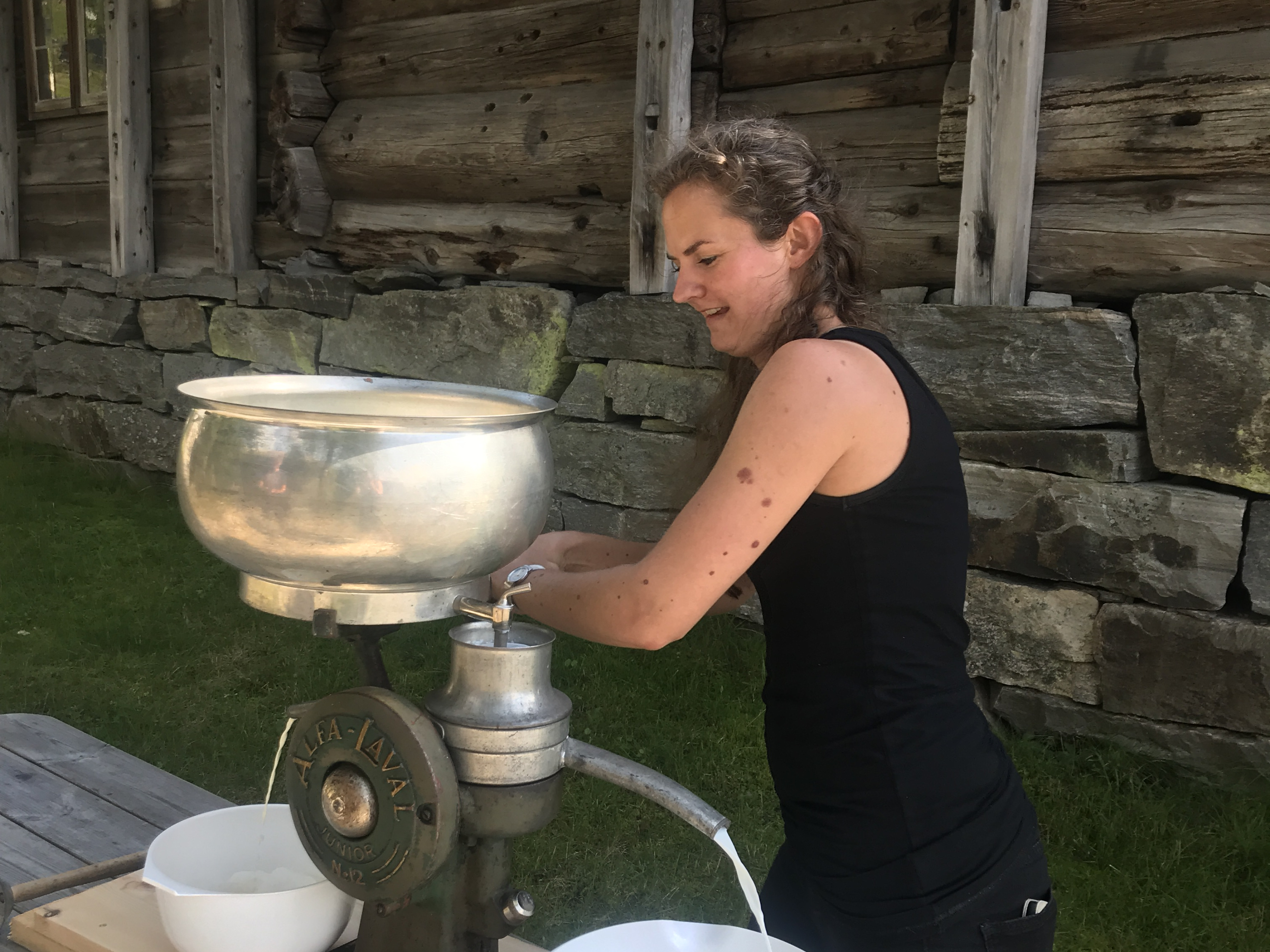 Kvinne står og separerer mjølk med ein mjølkeseparator.