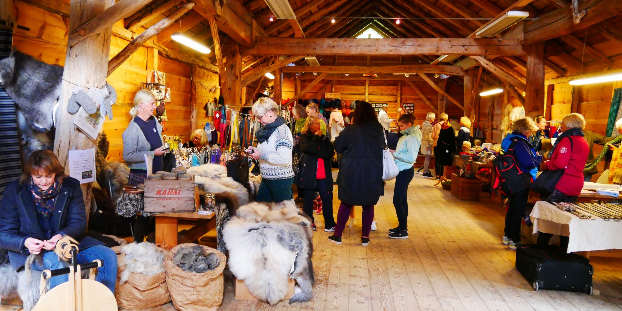 Frå husflidsmesse. Besøkande og utstillarar i løe.