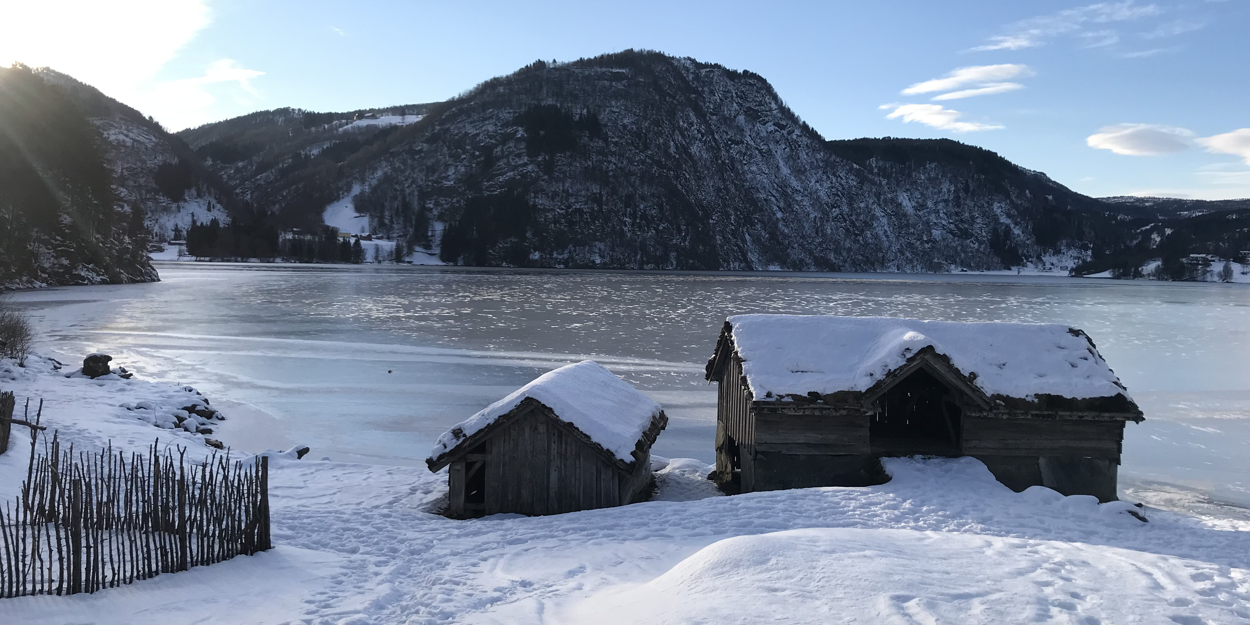 Vinter i friluftsmuseet. Utsikt mot Movatnet og nausta. Is på vatnet.
