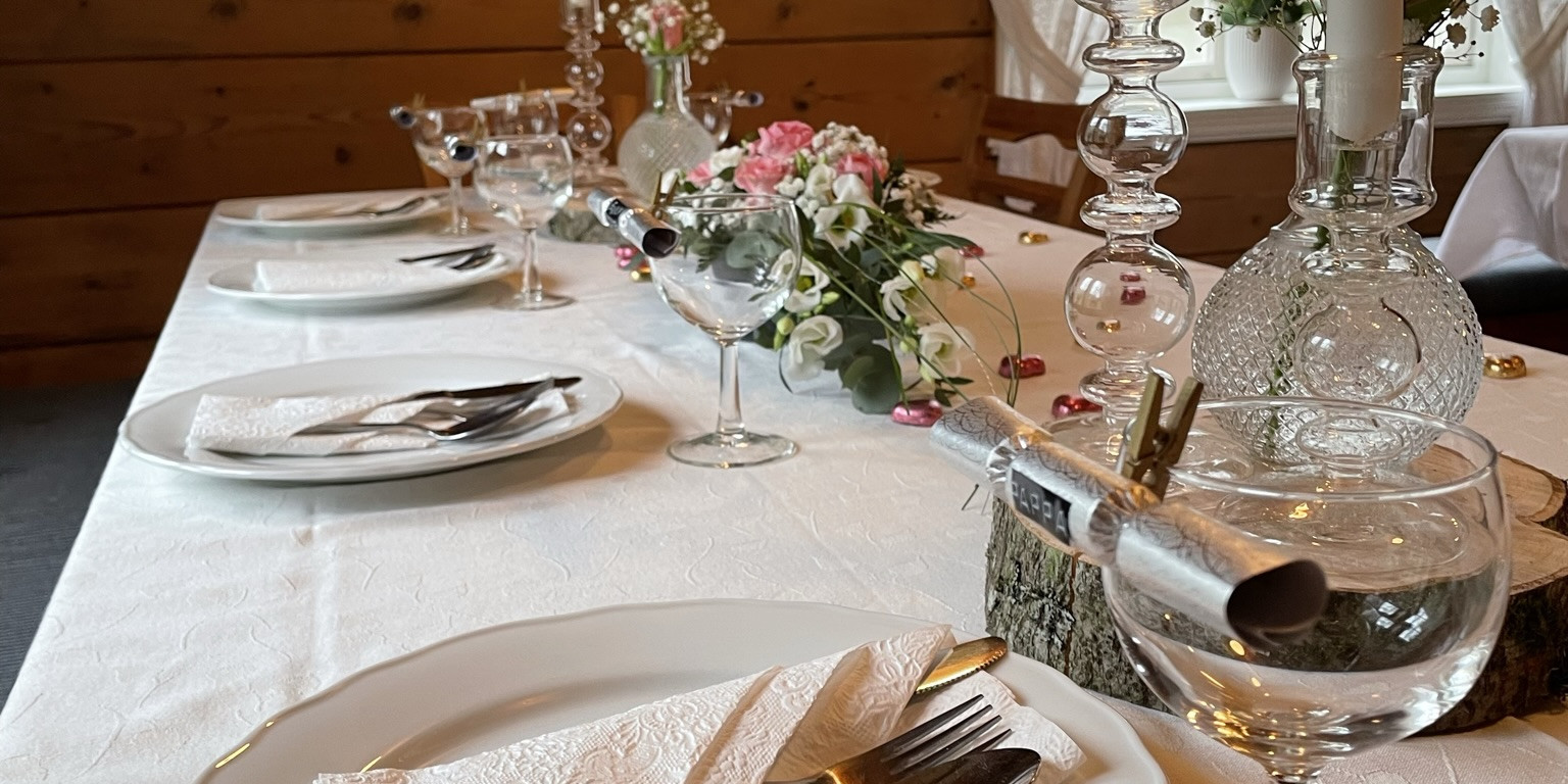 Dekorert bord i Halbrendshuset. Bordet er dekka og pynta med duk, serviettar, blomar og lysestaker.