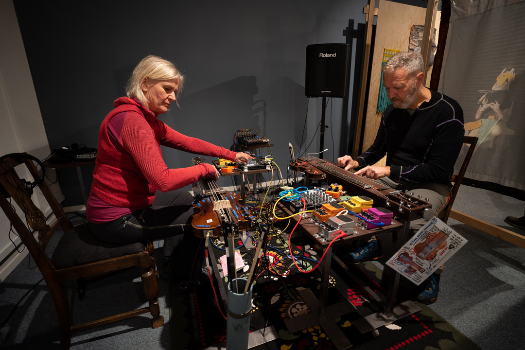 To vaksne spelar på instrument.